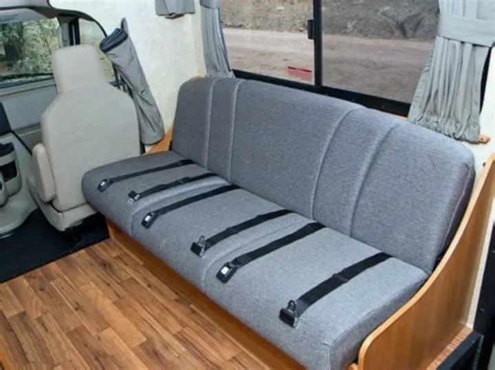 Gray upholstered bench seat with multiple black seatbelts, wood floor inside an RV rental. Ideal for passenger comfort.. Thor Majestic 2018