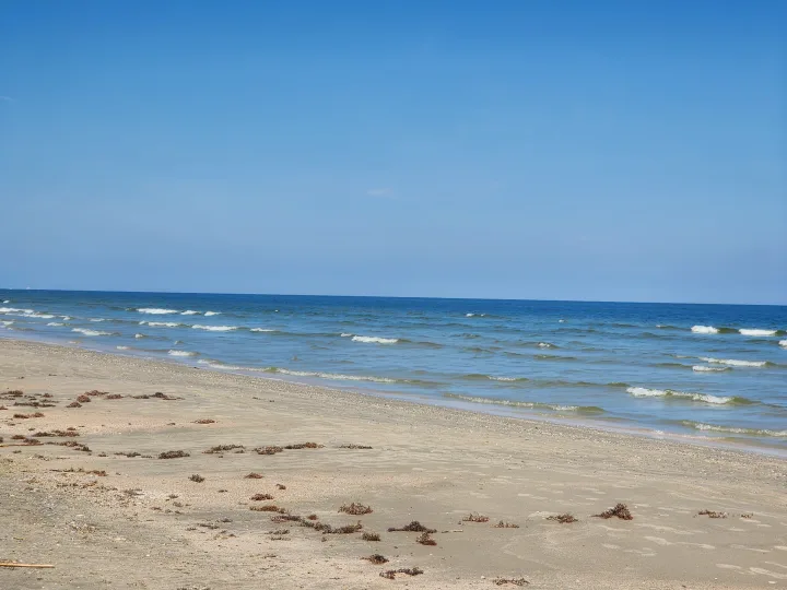 A pristine beach scene with clear blue sky, gentle ocean waves, and sandy shoreline. Ideal for an RV rental vacation.. Keystone RV Hideout 2023