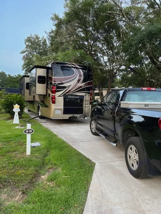 Venetian RV rental motorhome parked at site D19, slides out, with a black pickup truck on the driveway at an RV park.. Thor Venetian 2017