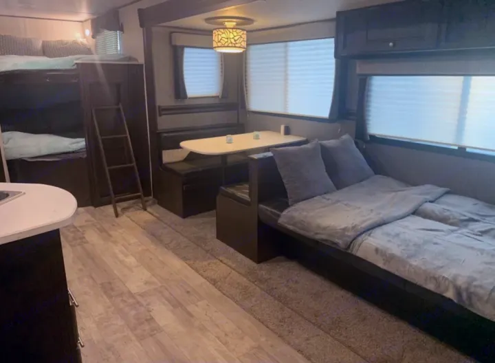 Cozy rv rental interior showcasing bunk beds, dinette, and sofa bed. Perfect for family adventures.. Heartland Pioneer 2020