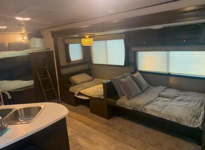 Inside an RV rental: bunk beds, convertible sleeping areas, kitchen sink, and windows with blinds offer a cozy space.. Heartland Pioneer 2020