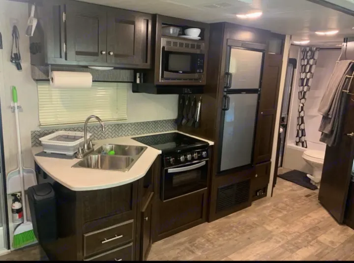 This RV rental offers a compact kitchen with a sink, stove, and microwave, plus a full bath, ideal for travel comfort.. Heartland Pioneer 2020