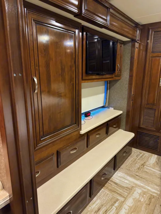 Explore the comfortable RV rental interior: dark wood cabinetry, TV, storage bench, and modern tiled flooring.. Thor Venetian 2017