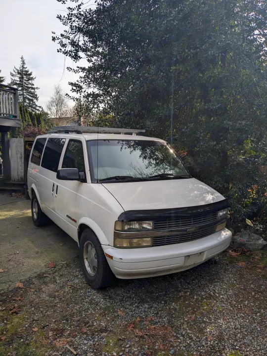 White AWD Chevy Astro van, perfect for RV rental adventures, parked on a gravel driveway.. Chevrolet Open Road 2002