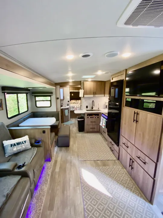 Explore this stylish RV rental interior, featuring a full kitchen, dinette, living area with recliners, and cozy bedroom.. Grand Design Imagine 2023