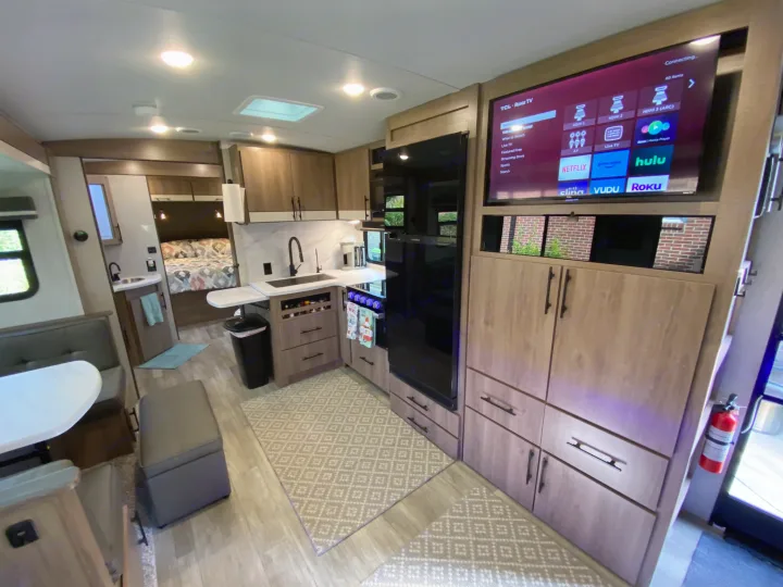Spacious, modern RV rental interior with kitchen, dining, TV with streaming apps, and bedroom area.. Grand Design Imagine 2023