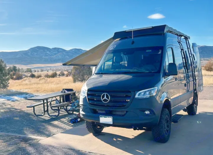 Rugged Mercedes Sprinter camper van (RV rental) parked with awning open. Scenic mountains & picnic table visible.. Antero Adventure Motors Antero Adventure Motors Class B 2022