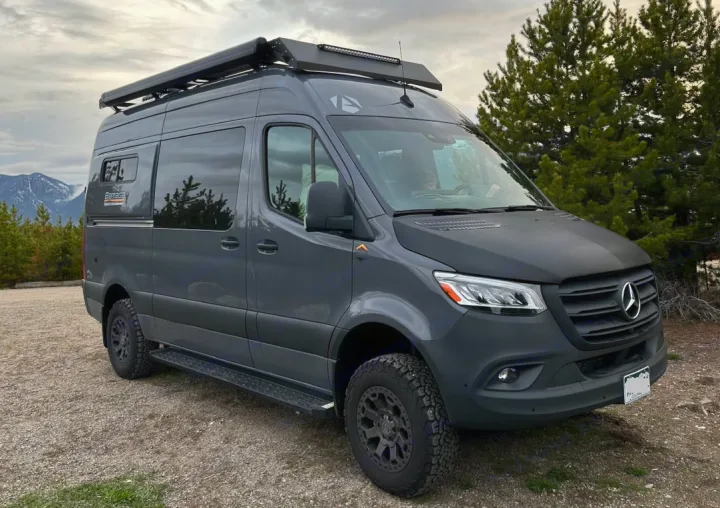 Dark grey Mercedes-Benz Sprinter adventure van, ideal for rv rental. Rugged tires, roof rack, and light bar in a mountain setting.. Antero Adventure Motors Antero Adventure Motors Class B 2022