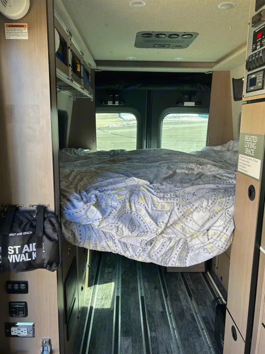 Inside an RV rental: a comfy bed awaits, with climate control, utility panels, and floor tracks for gear.. Antero Adventure Motors Antero Adventure Motors Class B 2022