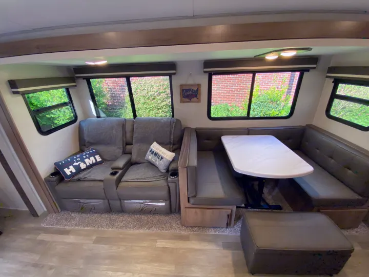 Spacious RV rental interior with comfortable recliners and a dining booth, ideal for family trips.. Grand Design Imagine 2023