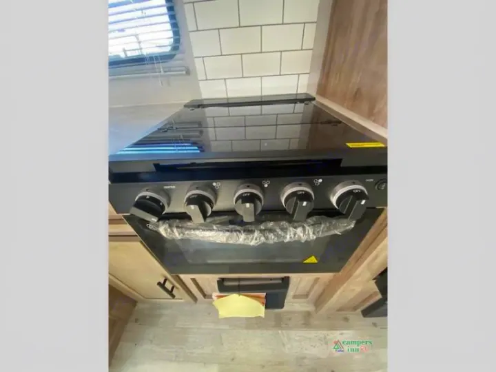 This RV kitchen features a sleek black glass cooktop and oven unit, perfect for an rv rental.. Gulf Stream Friendship 268BH 2024