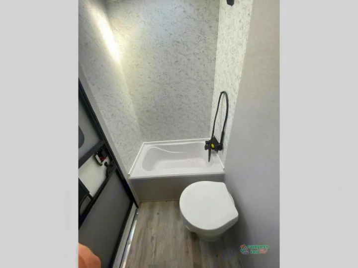 This compact RV rental bathroom features a small tub/shower combo, toilet, and light patterned walls.. Gulf Stream Friendship 268BH 2024