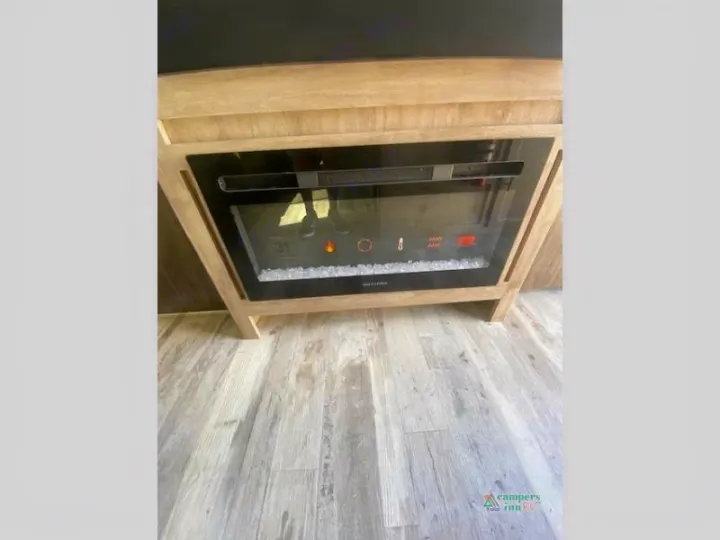 Inside an RV rental: a modern electric fireplace with faux crystals & digital display. Comfort for your road trip!. Gulf Stream Friendship 268BH 2024