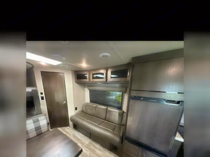 Spacious RV rental interior featuring a large fridge, comfortable sofa, dining area, and bunk beds.. Grand Design Other 2022