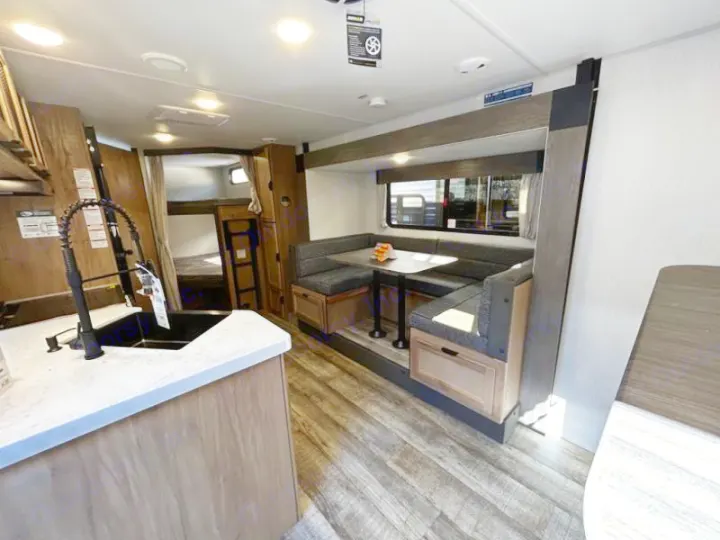 Spacious RV rental interior: modern kitchen, U-shaped dinette, and bunk beds visible. Perfect for family trips.. Forest River Cherokee Grey Wolf 23DBH 2024