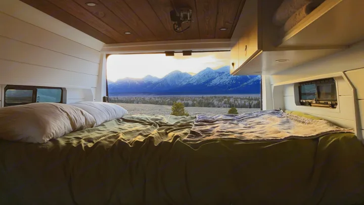 Relax in an RV rental bed with stunning views of snow-capped mountains at sunrise/sunset. Perfect for memorable adventures.. RAM ProMaster 2500 2022