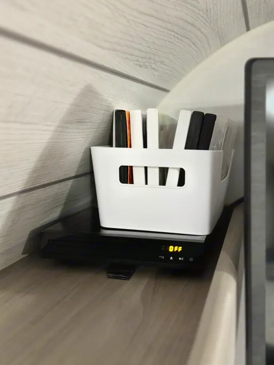 Inside an RV rental: A white storage bin holds movie cases, with a portable DVD player displaying "OFF" below.. Coleman Lantern LT 17B 2024