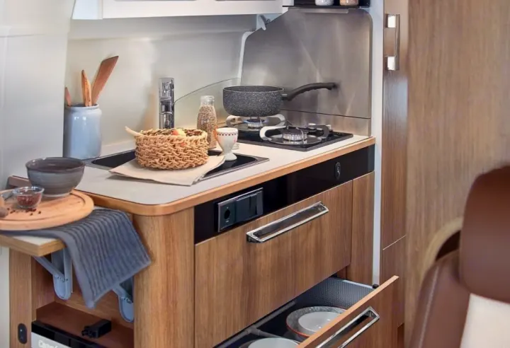 RV rental kitchen: a modern space with sink, two-burner stove, and sleek wood cabinets offering efficient storage.. CAMPEREVE FAMILY VAN 2022