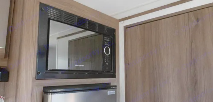 RV rental amenities: Greystone microwave & Everchill fridge integrated into modern wood-grain cabinetry, perfect for travel.. Cruiser RV Hitch 2024