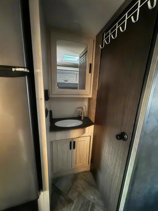 RV rental: Compact bathroom with vanity sink, mirror, and hooks on an adjacent door, maximizing small space.. Forest River Sunseeker LE 2022