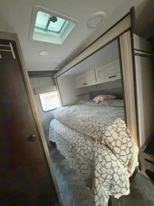 RV rental: Compact bedroom showing patterned blanket on bed, overhead storage, window, and roof vent.. Forest River Sunseeker LE 2022