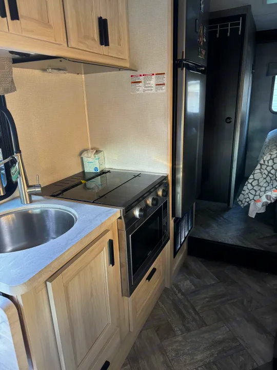 This RV rental offers a compact kitchen with a sink, stovetop, microwave, and fridge, plus wood-look flooring.. Forest River Sunseeker LE 2022