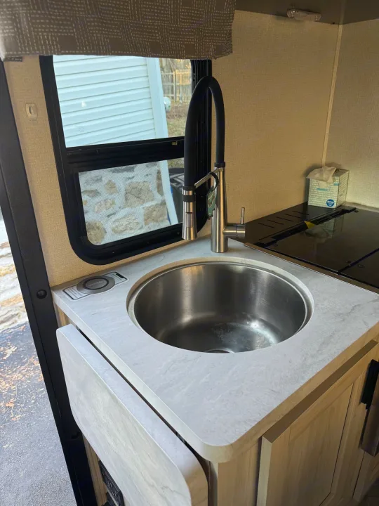 This RV rental kitchen features a sleek sink, stove, and ample counter space, including a pull-out extension.. Forest River Sunseeker LE 2022