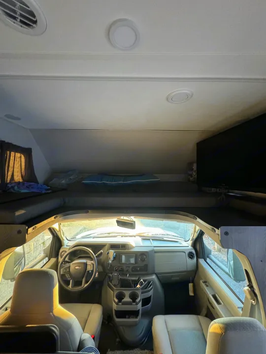 Inside an RV rental, featuring the driver's cab, an overhead sleeping area, and entertainment TV.. Forest River Sunseeker LE 2022