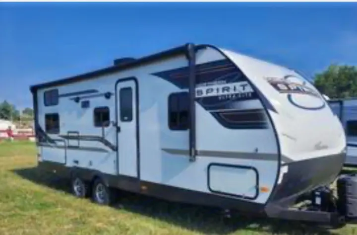 A sleek white and black Spirit travel trailer under a clear blue sky. Ideal for your next rv rental and outdoor adventures!. coachman spirit 2022