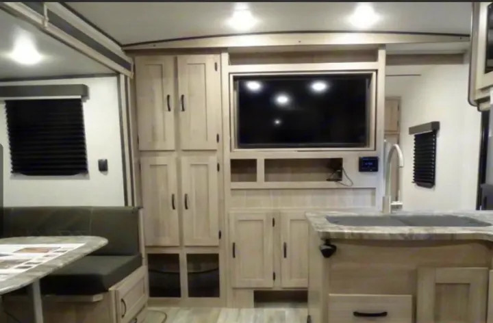 Inside an RV rental: modern interior with kitchen island, dinette, TV, and ample cabinetry. Compact and functional.. coachman spirit 2022