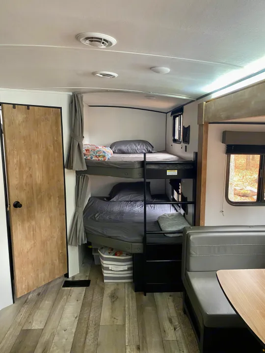 Cozy RV rental interior with bunk beds and a dining area, perfect for family adventures.. Keystone RV Springdale 2022