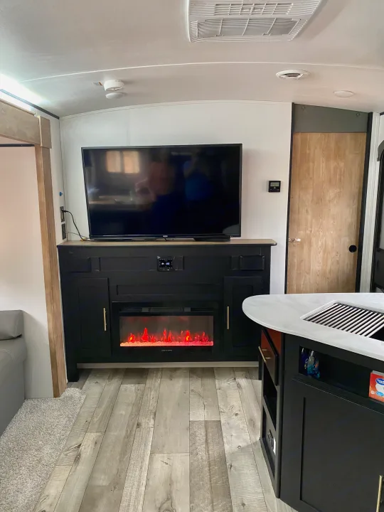 Spacious RV rental interior with TV, electric fireplace, and modern kitchen area.. Keystone RV Springdale 2022