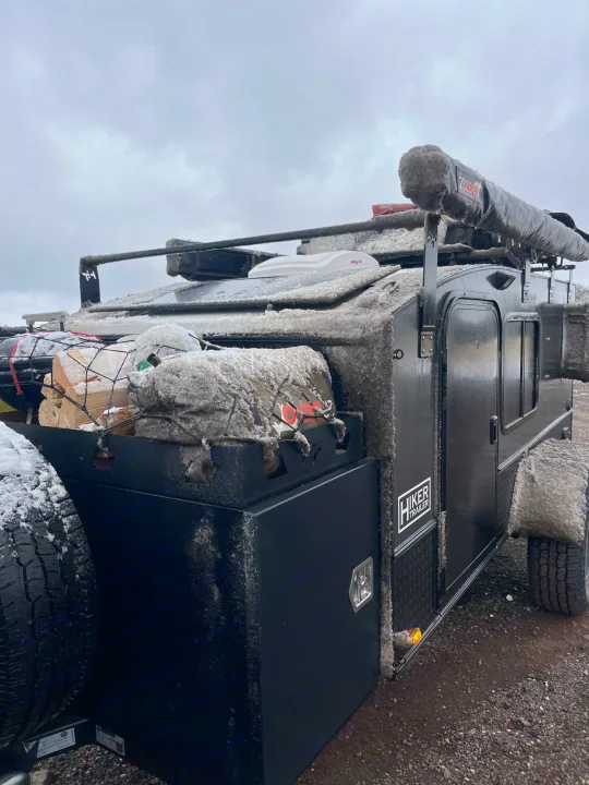 Icy Hiker Trailer RV rental, covered in snow and ice, with firewood, ready for rugged winter camping adventures.. Hiker MXL5x10 2022