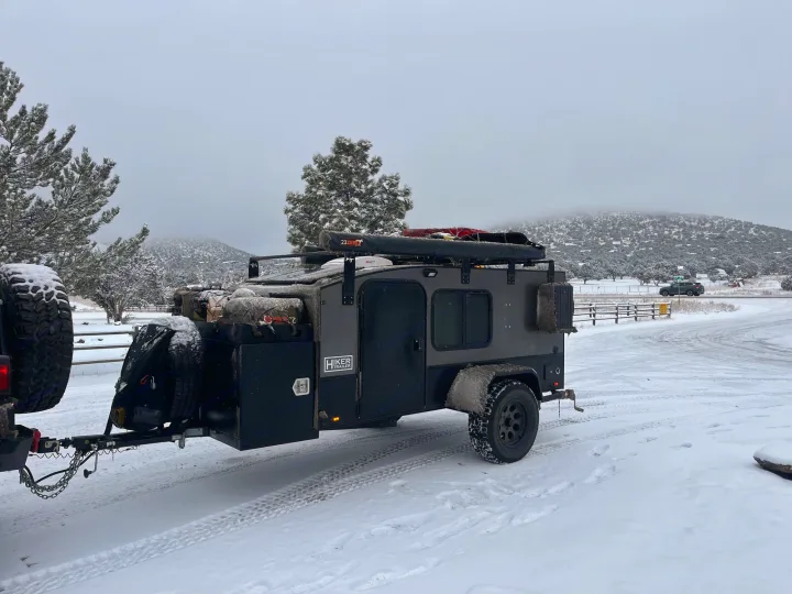 Snowy off-road Hiker Trailer, a robust RV rental, ready for winter camping adventures in rugged landscapes.. Hiker MXL5x10 2022