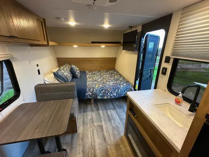 Cozy rv rental interior with a bed, dinette, kitchenette, sink, and TV for comfortable travel.. Forest River Cherokee Wolf Den 16 EV 2024