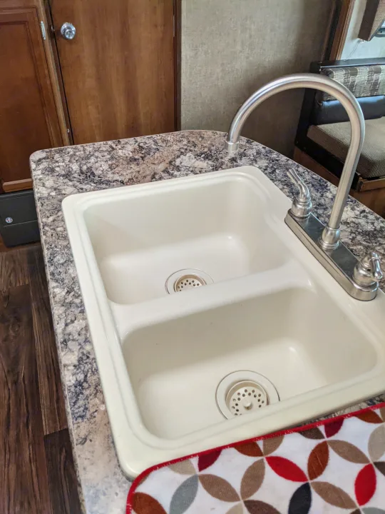 This RV rental kitchen features a cream double sink, chrome faucet, and speckled countertop, essential for travel.. Other Other 2015