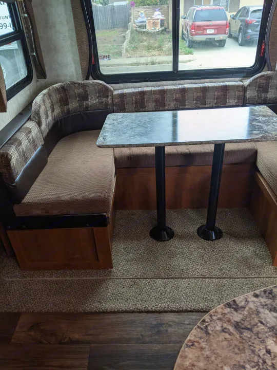 U-shaped dinette in an RV rental with patterned cushions & table. Windows show a street, cars, & jet skis outside.. Other Other 2015