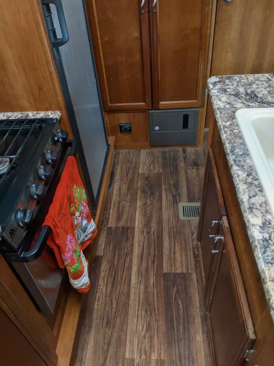 RV rental kitchen: compact interior with stove, fridge, sink, wood cabinets, and wood-look floor.. Other Other 2015