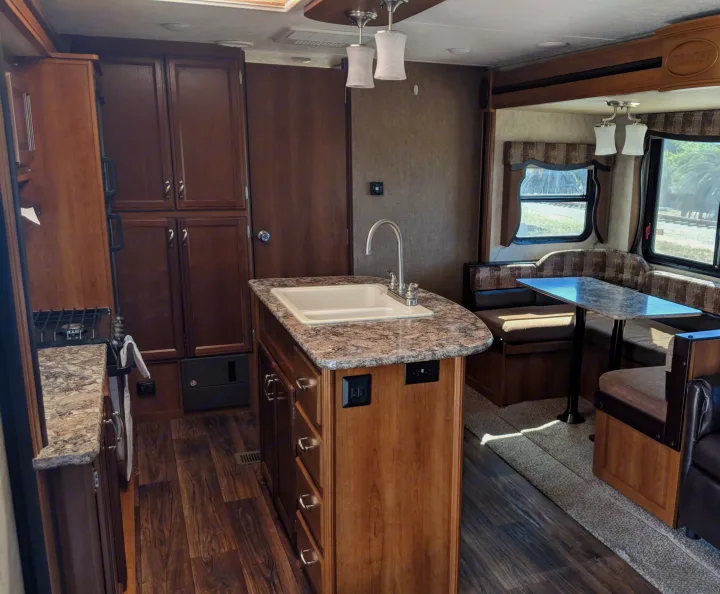 Spacious RV rental interior featuring a modern kitchen island with sink, stove, and comfortable dinette area for family meals.. Other Other 2015