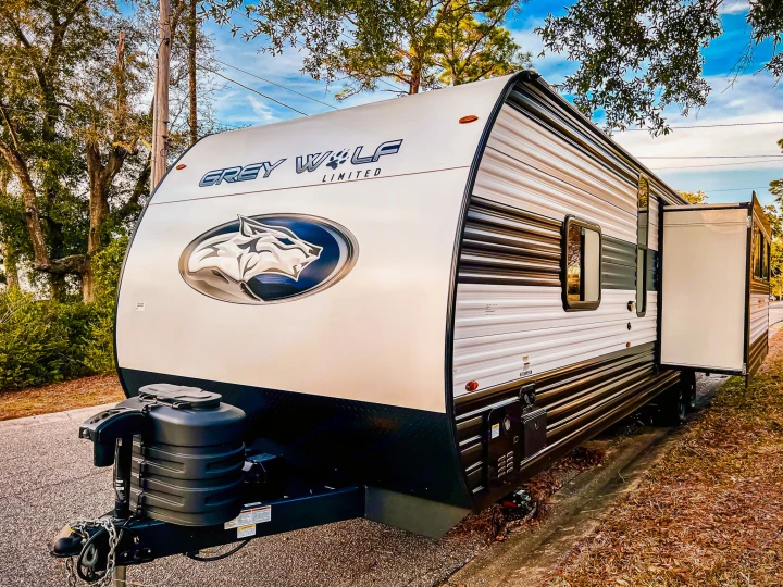 Discover this Grey Wolf Limited rv rental! This white and dark grey travel trailer, featuring a prominent wolf logo, is parked outdoors.. Forest River Cherokee Grey Wolf 2024