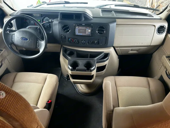 Clean Ford E-Series RV rental interior showing the driver's area, steering wheel, dashboard, stereo, and front passenger seat.. Adventurer Adventurer Motorhome 2012
