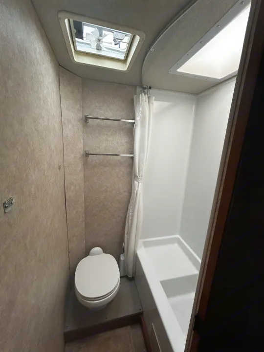 Compact RV rental bathroom with toilet, shower, towel bars, and overhead vents for light/air.. Adventurer Adventurer Motorhome 2012
