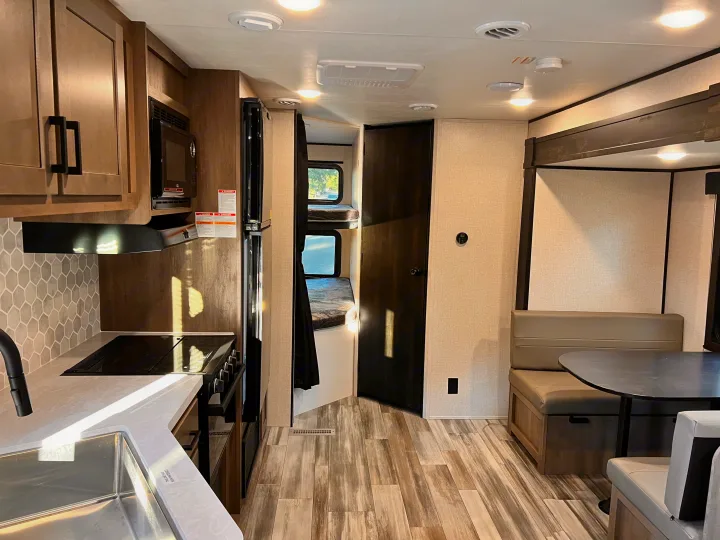 Modern RV rental interior showcasing a kitchen, dining booth, and bunk beds, featuring a bright, functional layout.. Starcraft Autumn Ridge 2024
