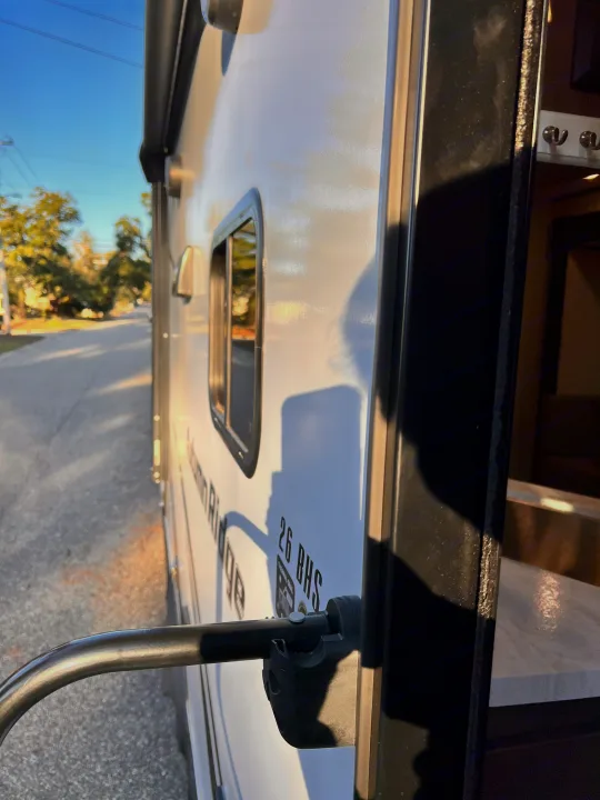 Sunlit RV rental: the 26 BHS travel trailer's open doorway, handrail, and exterior. Glimpse of the cozy interior.. Starcraft Autumn Ridge 2024