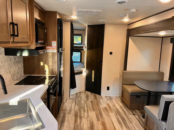 RV rental interior showcasing a full kitchen with sink/stove, a cozy dinette, and private bunk beds. Modern and functional space.. Starcraft Autumn Ridge 2024