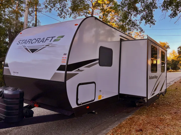 Starcraft Autumn Ridge travel trailer, an RV rental, parked with its slide-out extended on a sunny day.. Starcraft Autumn Ridge 2024