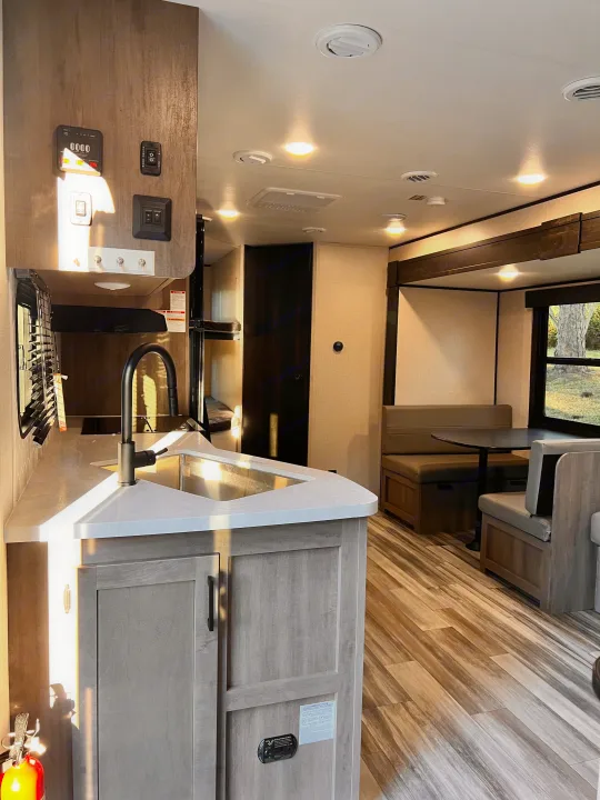 Bright rv rental interior featuring a stylish kitchen with sink, cozy dinette, and bunk area for a great travel experience.. Starcraft Autumn Ridge 2024