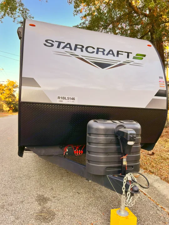 Front view of a Starcraft travel trailer, perfect for an RV rental, highlighting the propane tank and hitch assembly.. Starcraft Autumn Ridge 2024