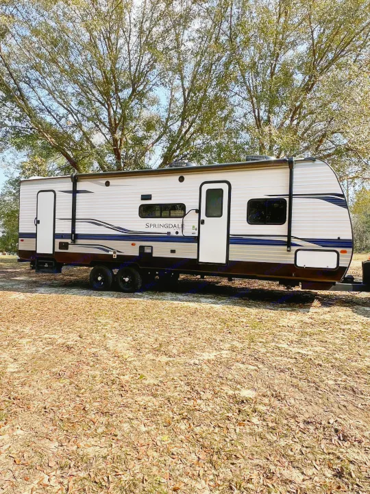 Spacious Springdale travel trailer available for RV rental, parked outdoors amidst trees and fallen leaves.. Keystone RV Springdale 2022