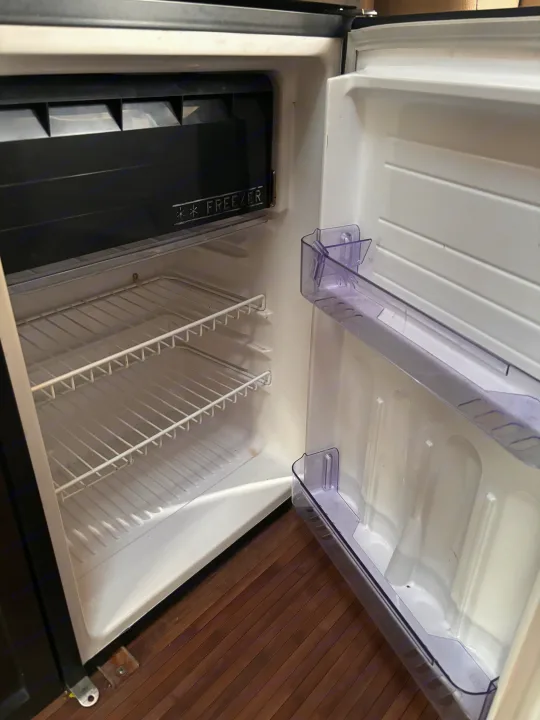 Interior of a compact, empty refrigerator with a freezer compartment and wire shelves, typical for an RV rental.. Mercedes-Benz Sprinter RV Motorhome Campervan 2017